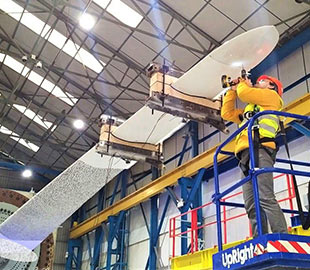 Two men working on a turbine blade in a factory